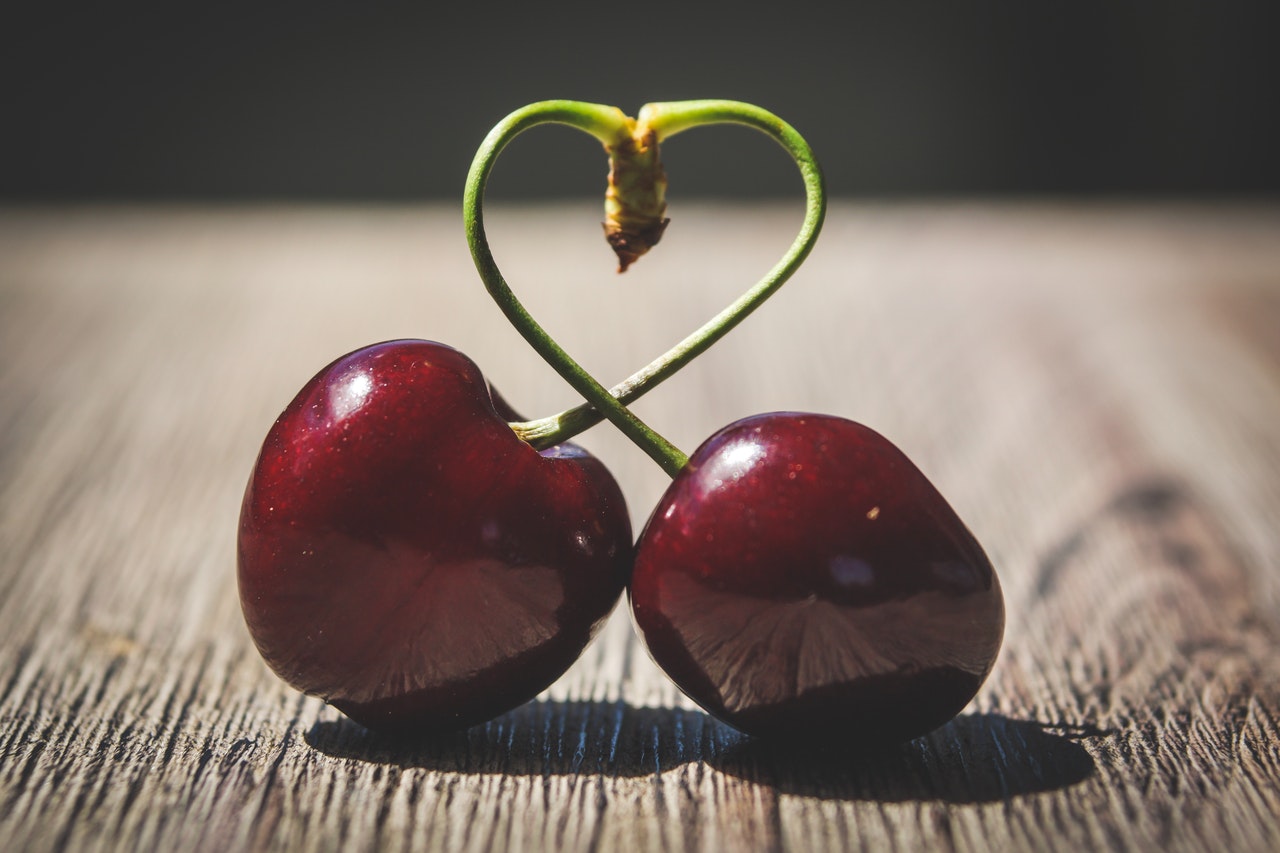 two-red-cherries-on-brown-surface